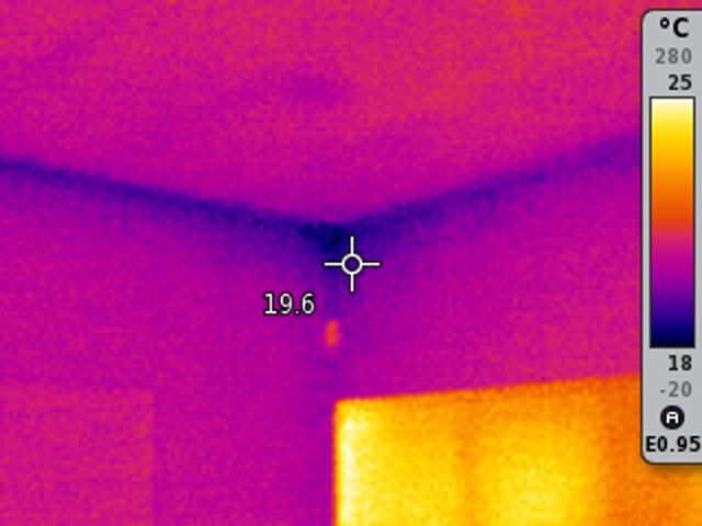 Pohled z interiéru domu ukazující tepelné mosty konstrukce kolem stropu. Ukazuje, že stříkaná pěna na úrovni stropu udržuje teplo uvnitř domu.